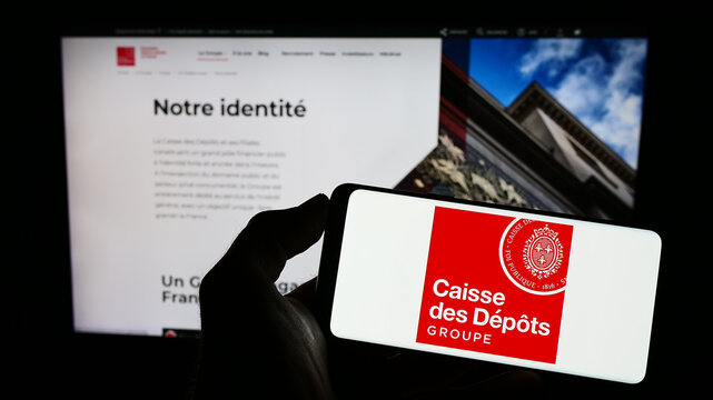Stuttgart, Germany - 03-12-2023: Person holding mobile phone with logo of Caisse des Depots et Consignations (CDC) on screen in front of web page. Focus on phone display.