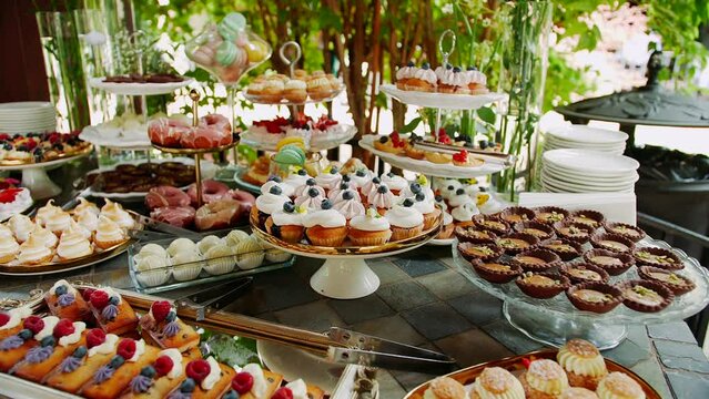 Large candy bar with various pastries and cupcakes on dessert table