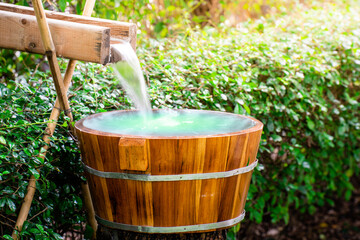 water flowing into a glass, Wooden barrels for natural onsen, steam hot water from natural hot springs, soft focus.