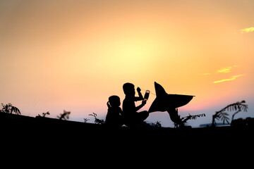 Fototapeta na wymiar Silhouette of rural children flying kites at sunset.