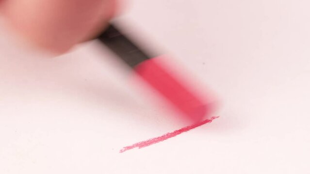 Drawing with a pink crayon on a piece of paper.