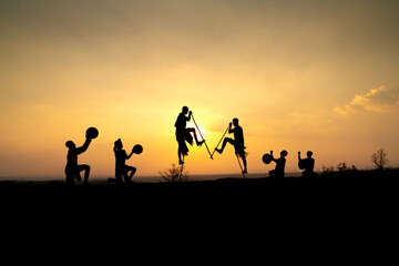 Obraz na płótnie Canvas Silhouettes of Ede boys and girls performing their traditional dance during sunset in Pleiku town, Gia Lai province, Vietnam.