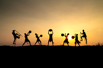 Silhouettes of Ede boys and girls performing their traditional dance during sunset in Pleiku town, Gia Lai province, Vietnam.