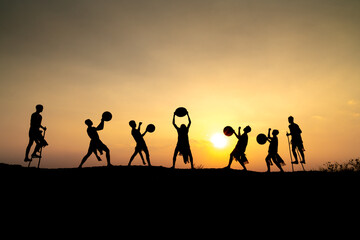 Silhouettes of Ede boys and girls performing their traditional dance during sunset in Pleiku town, Gia Lai province, Vietnam.