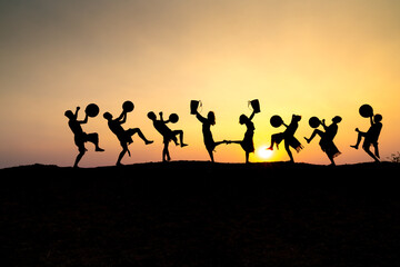 Silhouettes of Ede boys and girls performing their traditional dance during sunset in Pleiku town,...