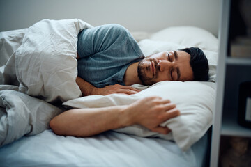 Peaceful man sleeping in bedroom.
