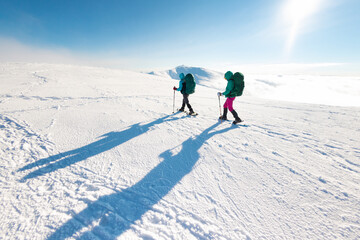 two tourists in winter mountains on snowshoes