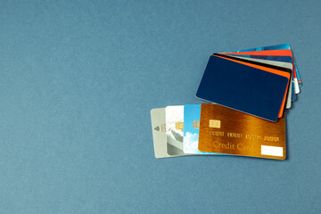 Credit cards of different issuers, gift cards, discount cards, sale cards fan out on a blue background. Pile of credit cards for different purposes