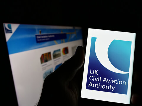 Stuttgart, Germany - 03-12-2023: Person holding smartphone with logo of British regulator Civil Aviation Authority (CAA) on screen in front of website. Focus on phone display.