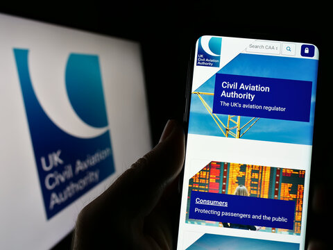 Stuttgart, Germany - 03-12-2023: Person holding cellphone with website of British regulator Civil Aviation Authority (CAA) on screen with logo. Focus on center of phone display.