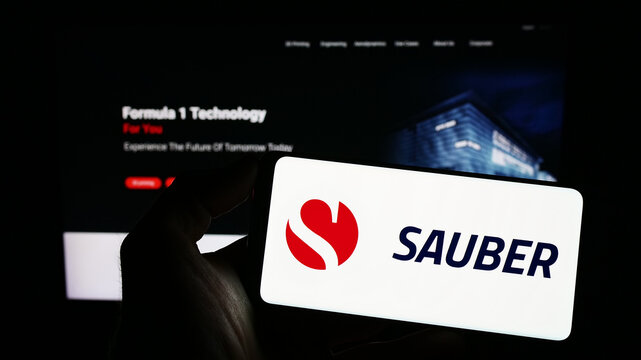 Stuttgart, Germany - 03-12-2023: Person holding mobile phone with logo of Swiss automotive company Sauber Motorsport AG on screen in front of web page. Focus on phone display.