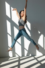 Asian dancer girl makes an acrobatic jump illuminated by the sun that enters through the window in an empty building. isolated