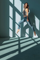 Asian dancer girl makes an acrobatic jump illuminated by the sun that enters through the window in an empty building. isolated