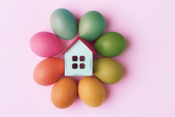 Decorative house and Easter eggs on pink background. Easter holiday greeting concept