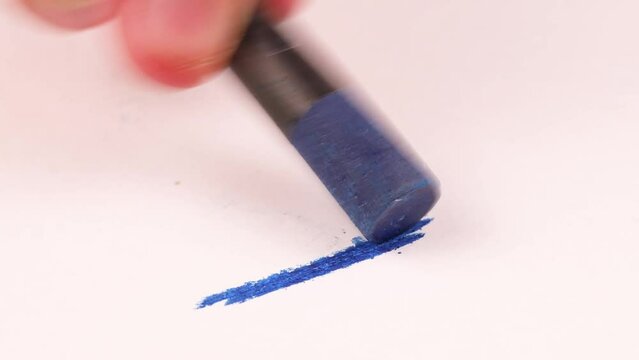 Drawing with a blue crayon on a piece of paper.
