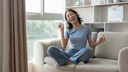 Young Asian woman happily listening to music through headphones, Woman was enjoying listening to her favorite music and rocking to the beat of the music, Stress relief, Happiness in life.