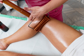 Young woman having leg massage with rollers in beauty spa salon, close up