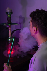 Man smoking shisha with purple background 