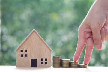 Mortgage,Model house and stack of coins money on natural green background,Business investment and real estate concept