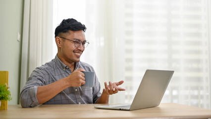 Professional Asian businessman siping coffee while having an online meeting with his team
