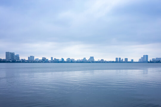 A view of Ho tay lake skyline in Hanoi Vietnam. It's a cloudy day and everything is in a shade of blue.
