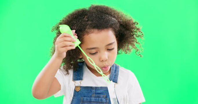 Children, bubble wand and a girl on a green screen background in studio playing with her toys. Kids, development and motor skills with a cute little female child blowing bubbles on a chromakey mockup