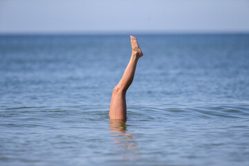 Drowning woman's legs sticking out of sea