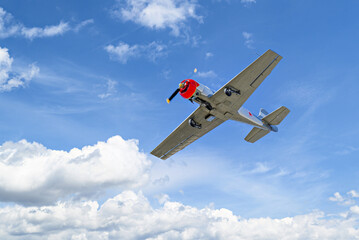 View of an acrobatic plane (aerodyne), in flight under a blue sky with white clouds. flight displays © Toni