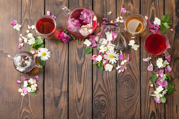 various teas with herbs and flowers on a dark wooden table, top view