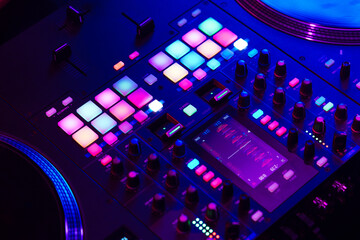 Close up of DJ mixing console in party light