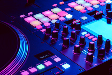 Close up of DJ mixing console in party light