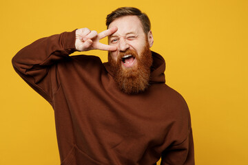 Young cheerful fun cool happy redhead caucasian man wearing brown hoody casual clothes show...