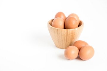 Several fresh chicken eggs placed in and out of a bamboo container on a white background. Copy space.