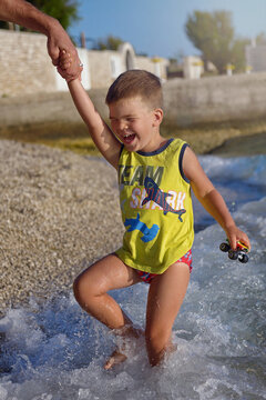 Happy boy jumping in the water on the beach playing playing with the waves in the sea and having fun , Croatia