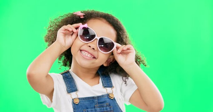 Happy, green screen and child with sunglasses in studio with cute, innocent and goofy attitude. Happiness, smile and portrait of girl with funky, fashion and stylish glasses by chroma key background.