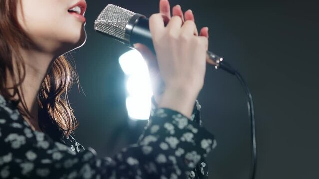 スポットライトを浴びて歌う女性　ライブ　コンサート　カラオケ