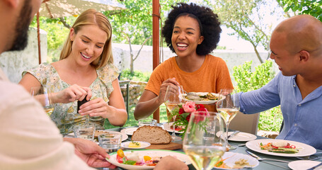 Naklejka premium Group Of Friends Enjoying Outdoor Meal And Wine On Visit To Vineyard Restaurant