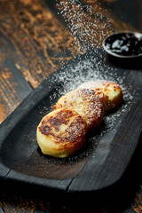 Ukrainian syrnyky on a wooden board on a wooden background, rustic style. fried cheese pancakes