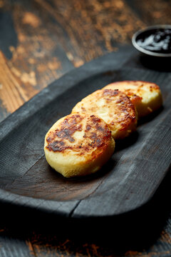 Ukrainian syrnyky on a wooden board on a wooden background, rustic style. fried cheese pancakes