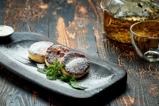 Ukrainian syrnyky on a wooden board on a wooden background, rustic style. fried cheese pancakes