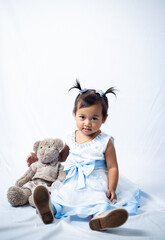 Little girl playing with her teddy beat isolated on white background. 