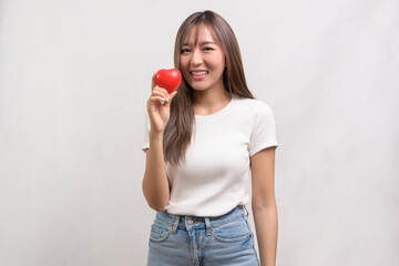 Portrait of young asian woman holding holding red heart shape over white background studio