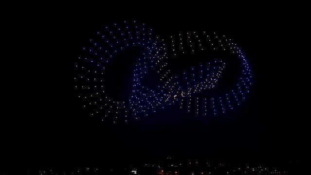 Flying drones creating 3d models moving on night sky over the city lights, exceptional show