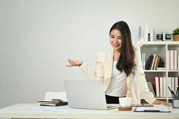 Shot of confident young female manager looking at laptop screen chatting online, communicating by conference video call