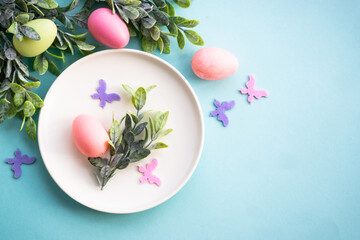 Easter table setting, Easter food background. White plate with eggs, spring flowers, green leaves and butterfly. Flat lay.