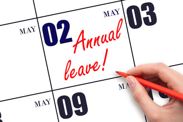 Hand writing the text ANNUAL LEAVE and drawing the sun on the calendar date May 2