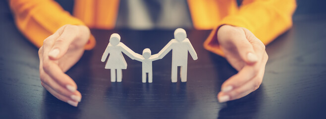 Figurine of the family surrounding by woman's hands.