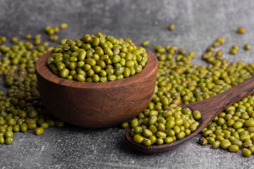 Dry green beans on wooden bowl and spoon. Organic raw green mung beans. Vigna radiata.