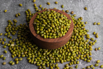 Dry green beans on wooden bowl and spoon. Organic raw green mung beans. Vigna radiata.