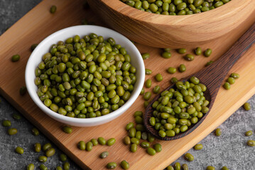 Dry green beans on wooden bowl and spoon. Organic raw green mung beans. Vigna radiata.